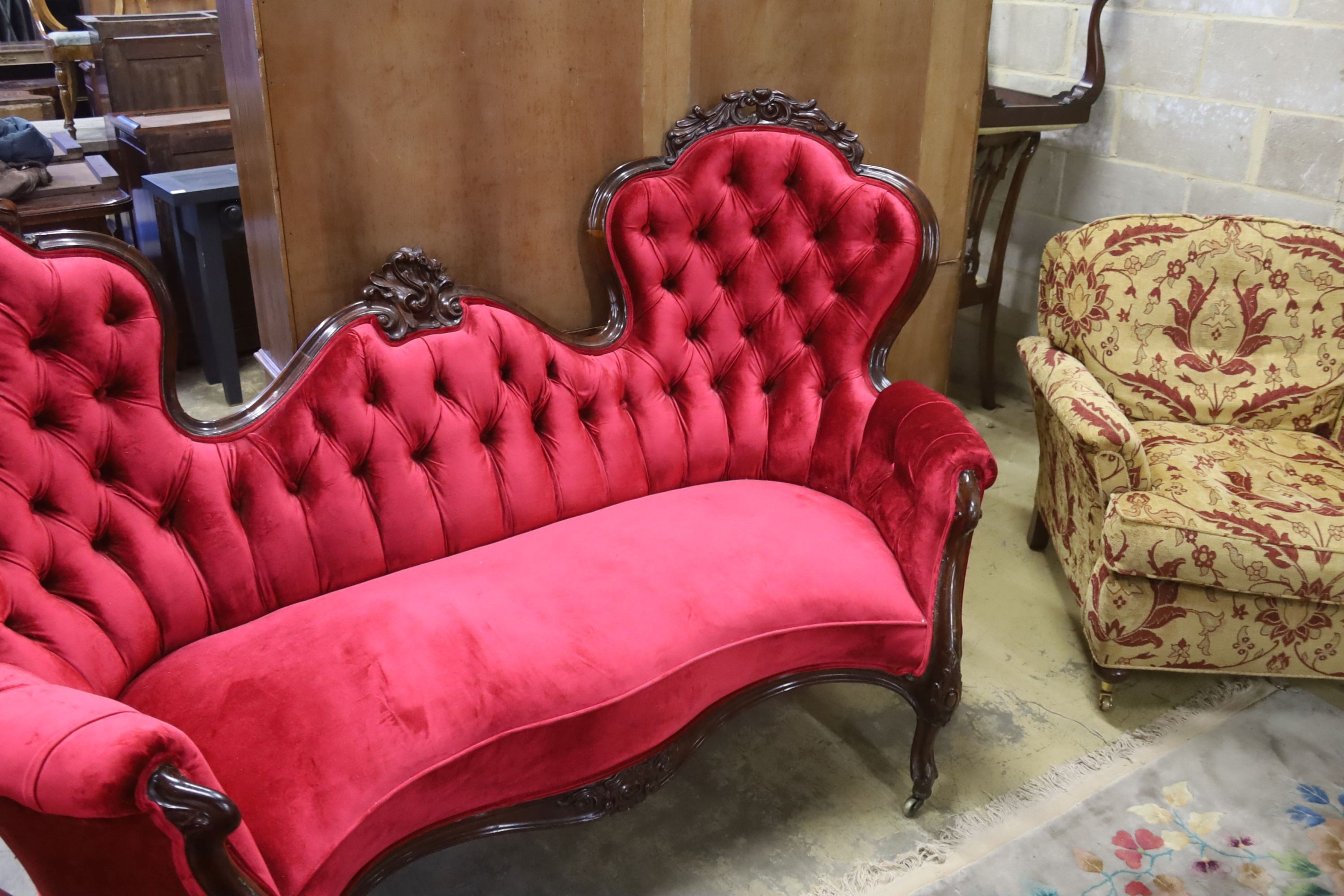 A Victorian carved rosewood double spoon back settee upholstered in deep buttoned scarlet velvet, length 200cm, depth 96cm, height 122cm